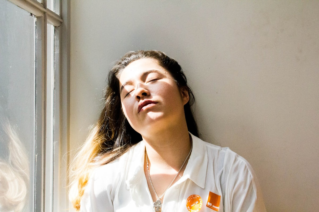 Woman standing at a window in daylight, considering hormone-free options for menopause
