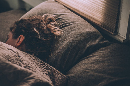 Woman asleep under blankets, deep sleep being the strongest lever on cortisol