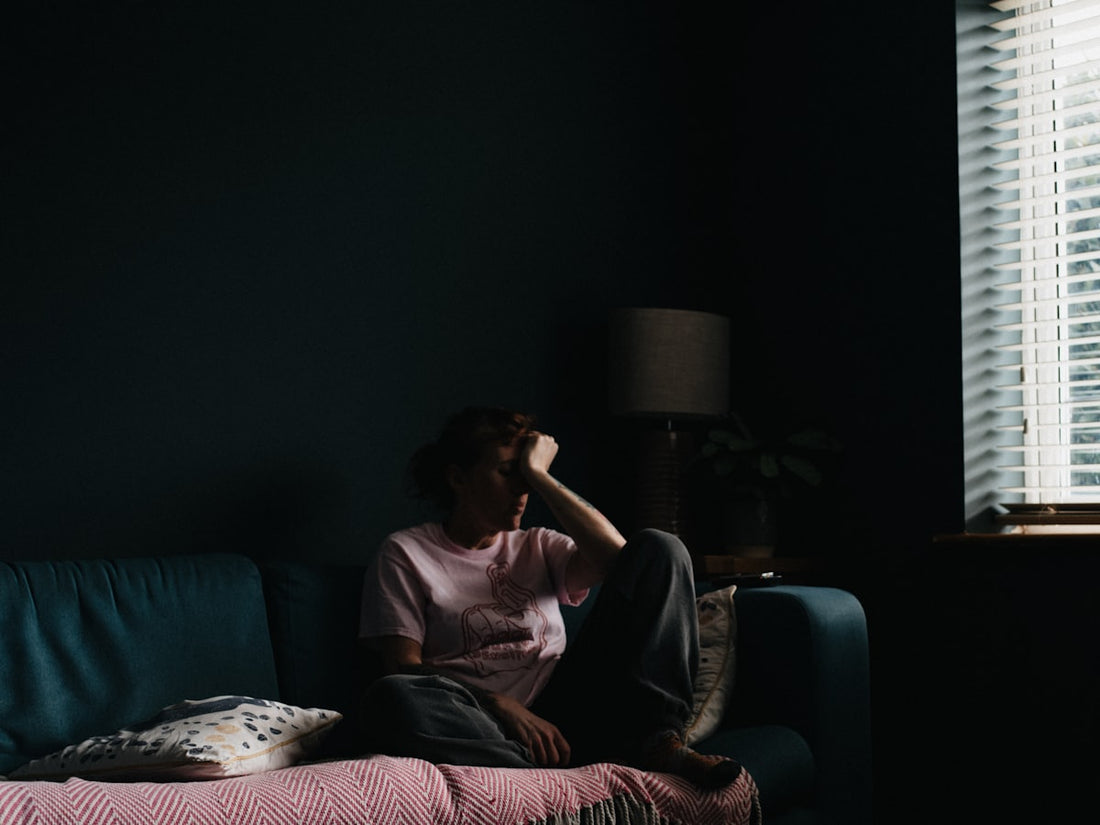 Woman in her forties sitting on a sofa looking exhausted during the day